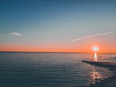 Cenova, İtalya - 26 Şubat 2021: Cenova Denizi üzerinde kış günleri güzel bir günbatımı. İnanılmaz kırmızı ve turuncu renkli gökyüzü suya yansıyor..