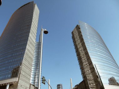 Milan, İtalya - 05 Mart 2021: Ofis ve gökdelenler parlak güneş ve açık mavi günbatımı arkaplanı. Ticari gayrimenkul. Modern iş şehri bölgesi. Dışarıdaki ofis binaları.. 