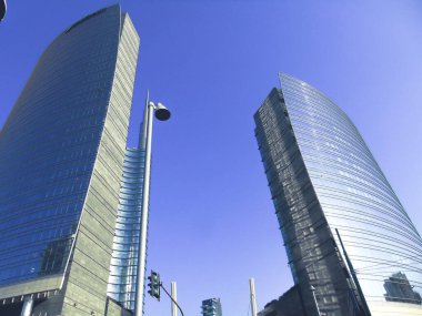 Milan, İtalya - 05 Mart 2021: Ofis ve gökdelenler parlak güneş ve açık mavi günbatımı arkaplanı. Ticari gayrimenkul. Modern iş şehri bölgesi. Dışarıdaki ofis binaları.. 