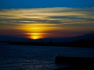 Cenova, İtalya - 10 Mart 2021: Cenova Denizi üzerinde kış günleri güzel bir günbatımı. İnanılmaz kırmızı ve turuncu renkli gökyüzü suya yansıyor..