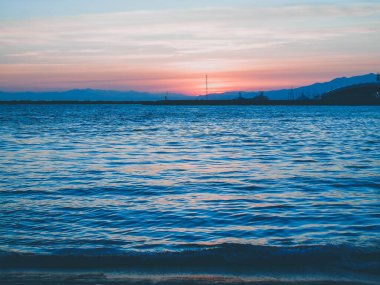 Cenova, İtalya - 10 Mart 2021: Cenova Denizi üzerinde kış günleri güzel bir günbatımı. İnanılmaz kırmızı ve turuncu renkli gökyüzü suya yansıyor..