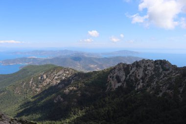 Elba, İtalya 01 Eylül 2021: Elba Adası 'ndan güzel yerler. Adanın havadan görüntüsü. Sahillerin yakınındaki küçük ünlü köyler. Yaz turistik yerleri. Arka planda bulutlar ve mavi gökyüzü.