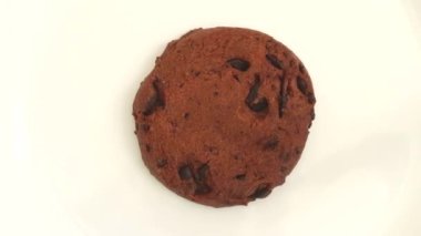 Biscuit with cocoa and coating drops rotates on the plate.