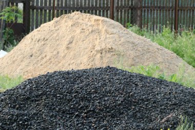 Beton yapmak için bir moloz yığını. Arka planda beton yapmak için bir kum yığını. Seçici odak.