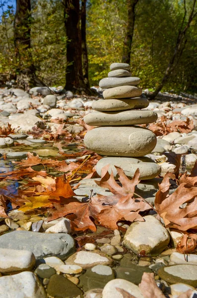 stack of rock balancing  in a river autumn season dry leaves around