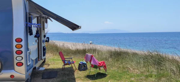 Yazın deniz kenarında bir karavan. Kumsal ağaçları. Mavi gökyüzü tatillerde seyahat ediyor.