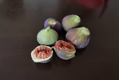 Tahta bir masada incir olgunlaşmış ve kahverengi arka planda olgun kesilmiş. 