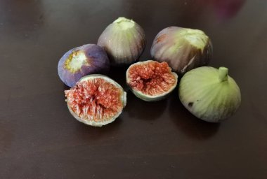 Tahta bir masada incir olgunlaşmış ve kahverengi arka planda olgun kesilmiş. 