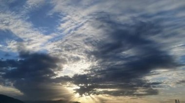 Güneş bulutların arasında ışık perdeleri yayılır.
