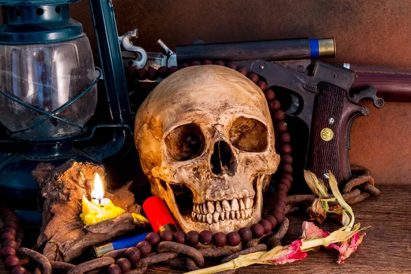 Naturaleza muerta, cráneos humanos con pistola de tiro, y lámpara en la mesa de madera —  Fotos de Stock
