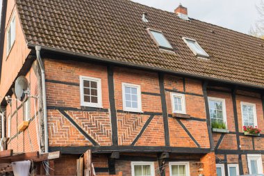 Geleneksel tuğla ve kereste kirişleri sergilenen klasik bir Fachwerk evinin önünde bir sıra park edilmiş araç. Sakin meskun sokaklar, miras mimarisi ve modern yaşamın bir karışımını yansıtıyor..