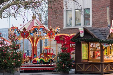 Almanya 'nın Kiel kentinde, bayram ışıkları ve süslenmiş köknar ağaçlarıyla klasik Noel pazarı atlıkarıncası. Tatil atmosferi ve geleneksel panayır eğlencesi.