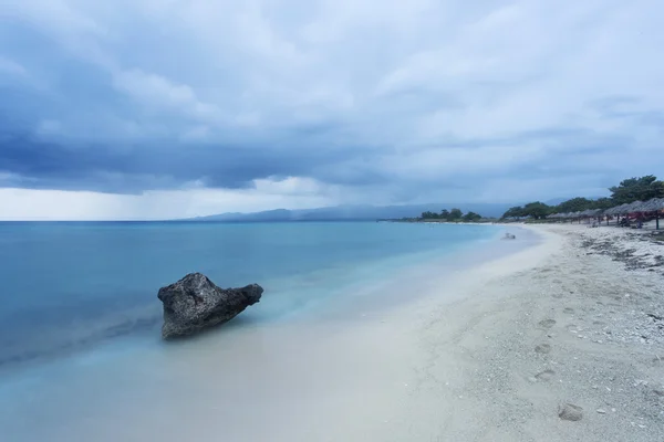 Rock on the beach with dramatic sky on square format — Stock Photo, Image