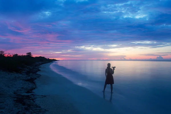 Photographe femme au lever du soleil sur une plage — Photo