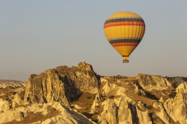 Kapadokya Türkiye 'de kayaların üzerinde uçan sıcak hava balonu