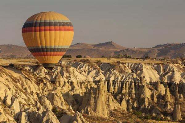 Globo de aire caliente volando sobre el paisaje rocoso en Capadocia Turquía —  Fotos de Stock