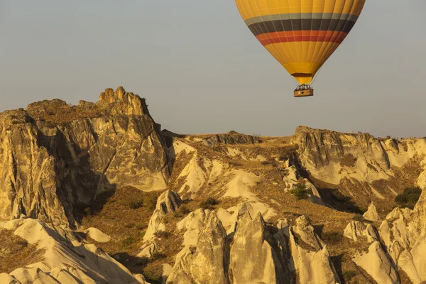 Balon na ogrzane powietrze latający nad skalistym krajobrazem w Cappadocia Turcja — Zdjęcie stockowe
