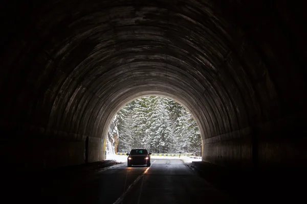 Carro entrando em um túnel com floresta no fundo com neve — Fotografia de Stock