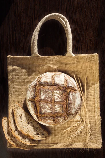 Bauernbrot und Weizen auf einer traditionellen Stofftasche — Stockfoto