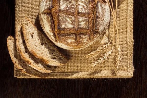 Bauernbrot und Weizen auf traditionellem Tuch — Stockfoto