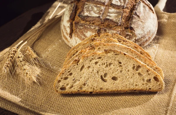 Bauernbrot und Weizen auf traditionellem Tuch — Stockfoto