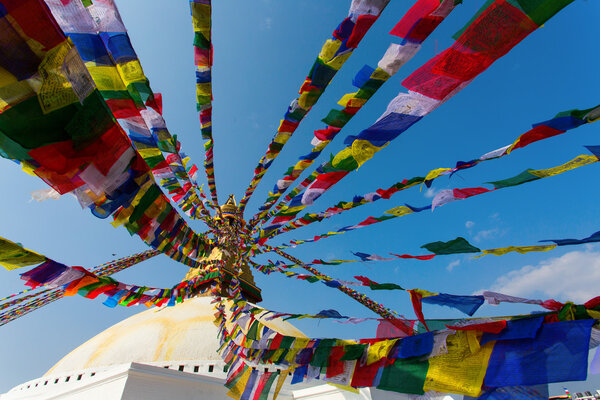 Prayer flags flying against the sun from the Boudhanath Stupa - symbol Kathmandu, Nepal.