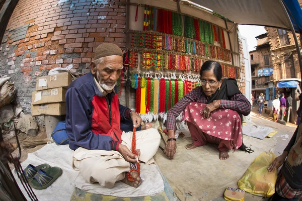 BHAKTAPUR, NEPAL - 20 DE NOVIEMBRE: Personas que trabajan y venden bienes — Foto de Stock