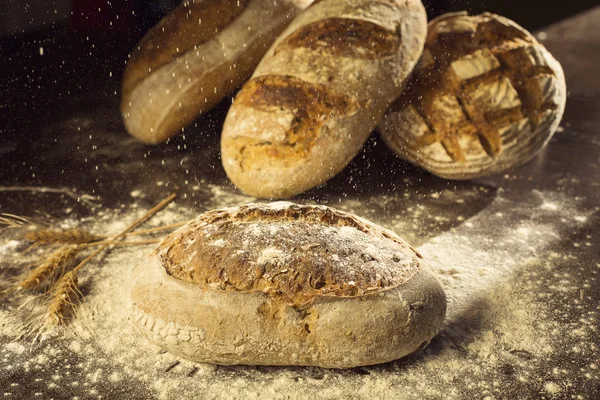 Rustikales Brot und Weizen auf schwarzem Tisch mit Mehl darauf und Poder — Stockfoto