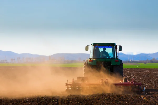 Трактор на закате вспахивает поле — стоковое фото