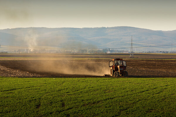 Tractor in sunset plowing the field