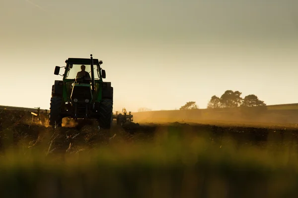 Traktor v sunset zorané pole — Stock fotografie