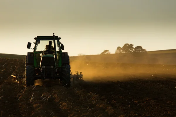 Tracteur au coucher du soleil labourant le champ — Photo