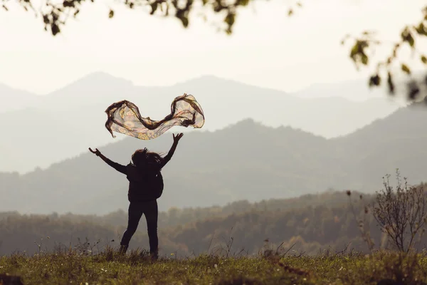 Beautiful young woman jumping on a green meadow with a colored tissue — Stock Photo, Image