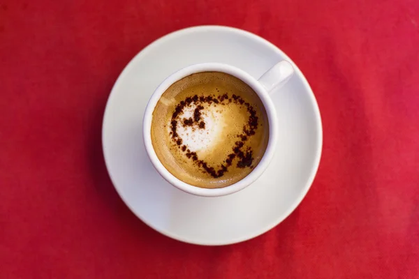 Koffiekopje met melk en hart vorm op rode achtergrond — Stockfoto
