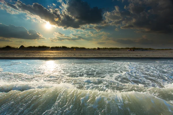 Deniz dalga köpüğü Sunset'teki çakıl plaj — Stok fotoğraf