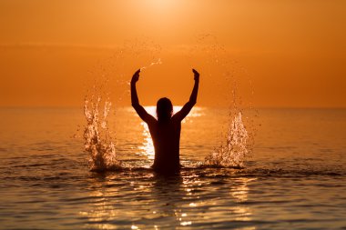 Adam sıçramasına suyla bir denizde bir gündoğumu ellerinde