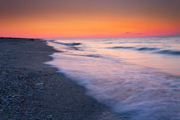 Красивые волны на закате над пляжем — стоковое фото