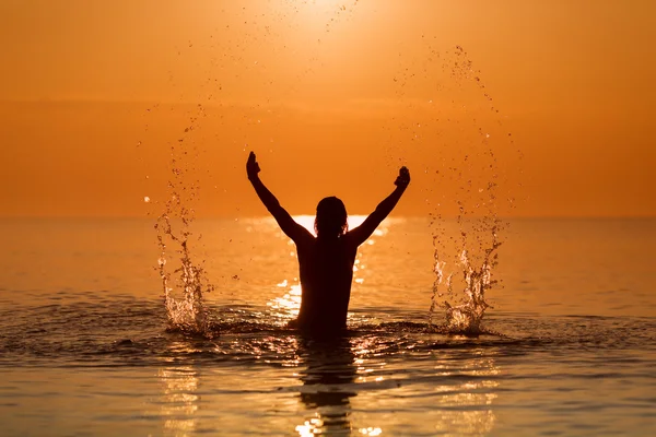 Ember fröccsenő víz a kezével, a tenger a sunrise — Stock Fotó