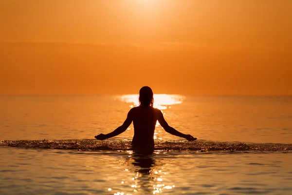 Man Splashing Water com as mãos em um mar ao nascer do sol — Fotografia de Stock