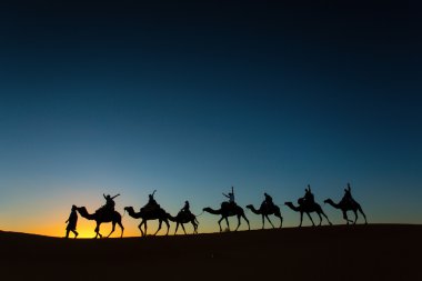 Sillhouette of camel caravan with happy peopple going through th clipart