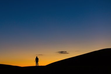 Sillhouette bir adam çölde gün batımında