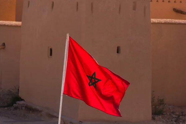 Размахивание тканевым флагом Марокко с традиционным зданием в задней части — стоковое фото