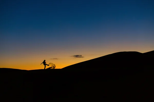 Gün batımında çöl kumları ile oynarken adam — Stok fotoğraf