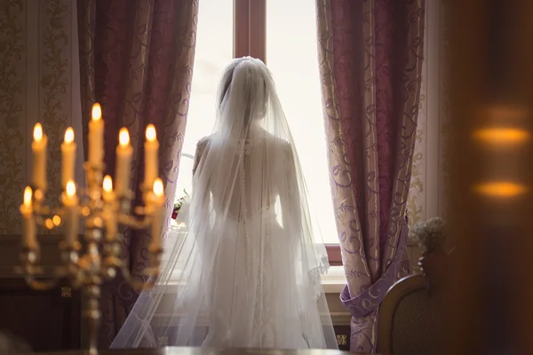 Portrait of the beautiful bride against a window indoors and can — Stock Photo, Image