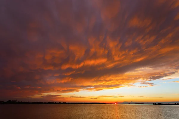 Red sunset over the sea, rich in dark clouds, rays of light — Stock Photo, Image