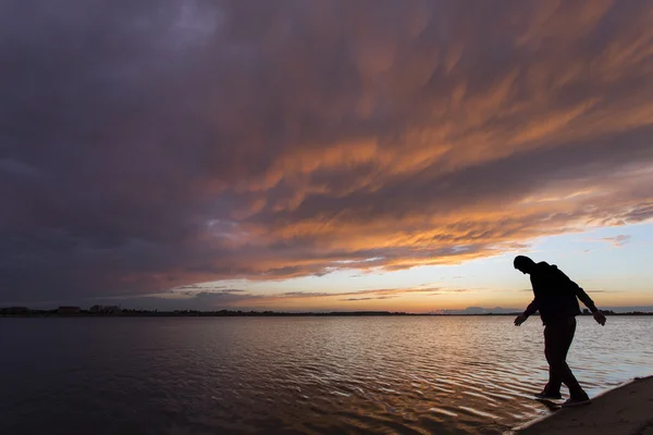Gün batımı su üzerinde yürümek, bir adam silüeti — Stok fotoğraf