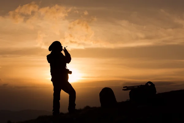 Silhouette of woman photographer smoking at sunset — Stock Photo, Image