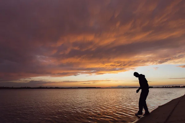 Silhouette of a man at sunset walking on water — Stock Photo, Image