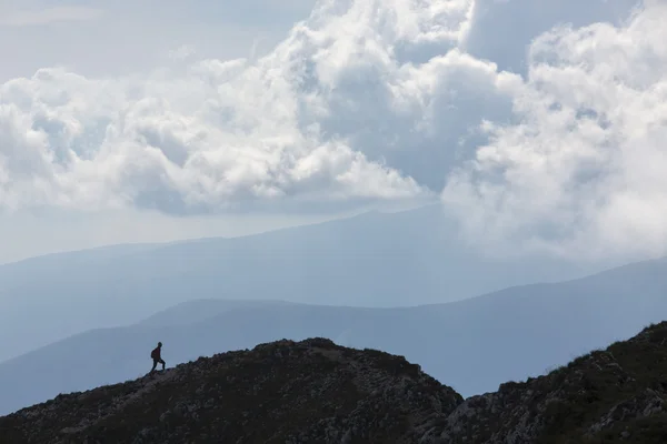 Σιλουέτα της αναρρίχησης νεαρός ενήλικας στην κορυφή της κορυφής με aer — Φωτογραφία Αρχείου