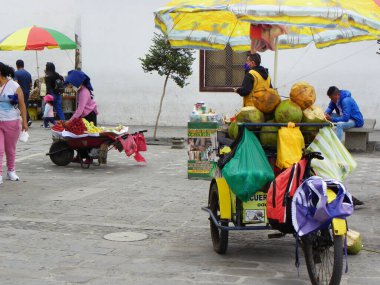 Cuenca, Ekvador - 14 Mart 2021: Taşıma arabalı sokak satıcıları meyve olarak yiyecek, San Francisco Plaza 'nın tarihi bölümünde kakao ürünleri sunuyorlar. Salgın sırasında koruyucu maskeli insanlar